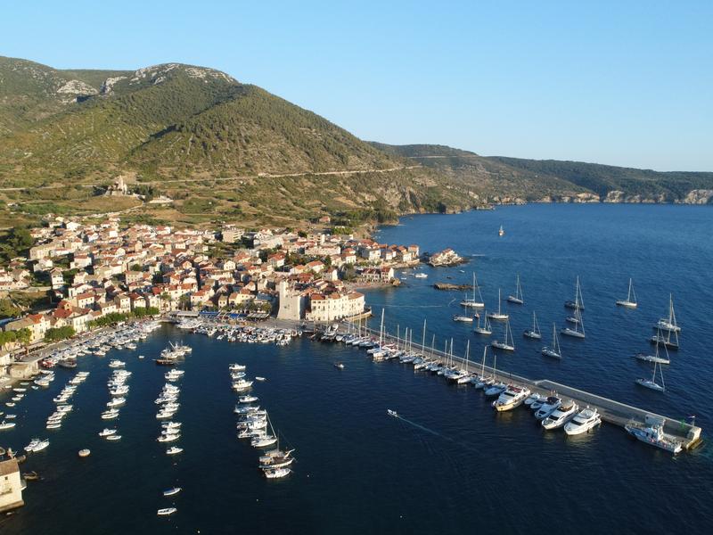 Yachts anchored in Komiža harbour with town and coastline of Vis island in the background